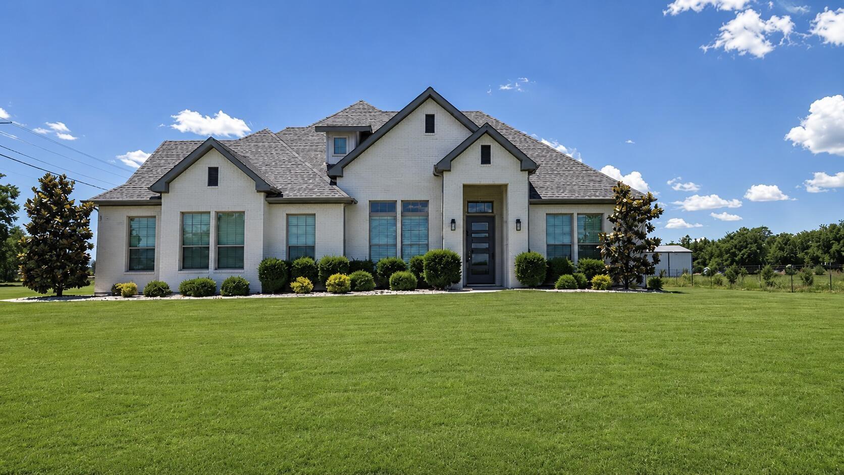 Light brick home with a broad front lawn in Anna, Texas