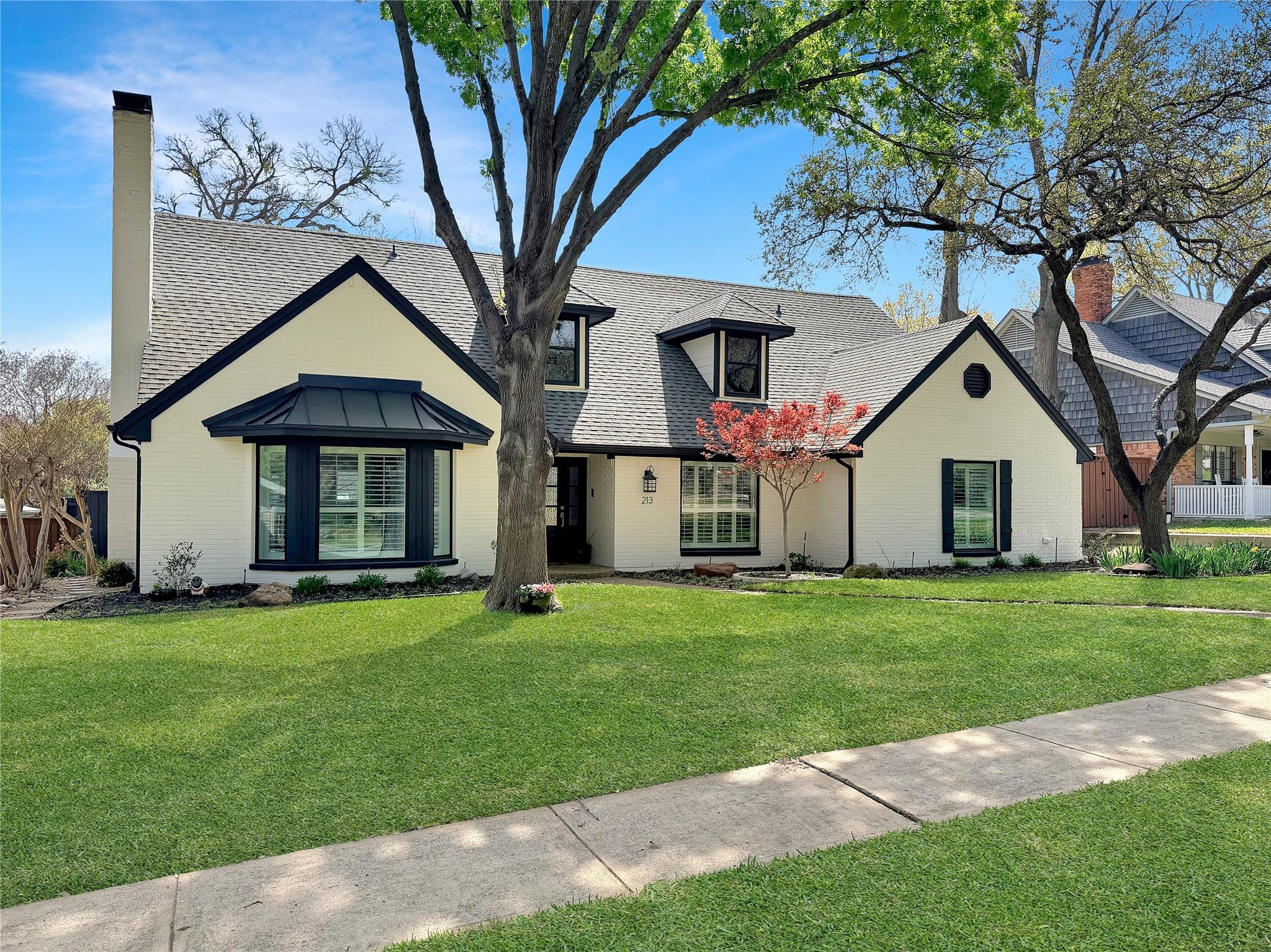 Light brick home with mature trees and a landscaped front yard in Richardson, Texas