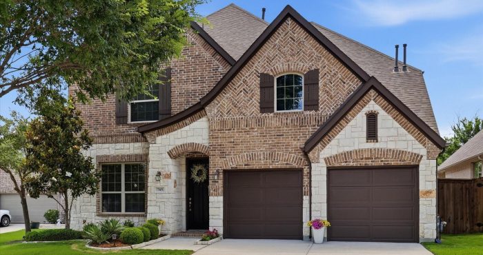 Two-story brick and stone home in Trinity Falls with a landscaped front lawn